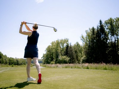 Eine Frau beim Abschlag eines Golfballs.