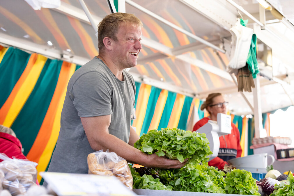 Ein Gemüseverkäufer auf einem Wochenmarkt.