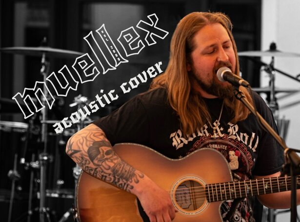 Eine Person mit langen, hellen Haaren sitzt auf einem Hocker und spielt eine akustische Gitarre. Sichtbar sind tätowierte Arme und ein schwarzes T-Shirt mit auffälligem Rockmusik-Motiv. Im Hintergrund steht ein Schlagzeug. Im oberen linken Bereich steht der Schriftzug 'muellex' in markanter, schräger Schrift sowie darunter 'acoustic cover'.