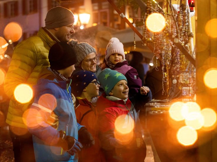 Familie vor einem Stand auf dem Weihnachtsmarkt.