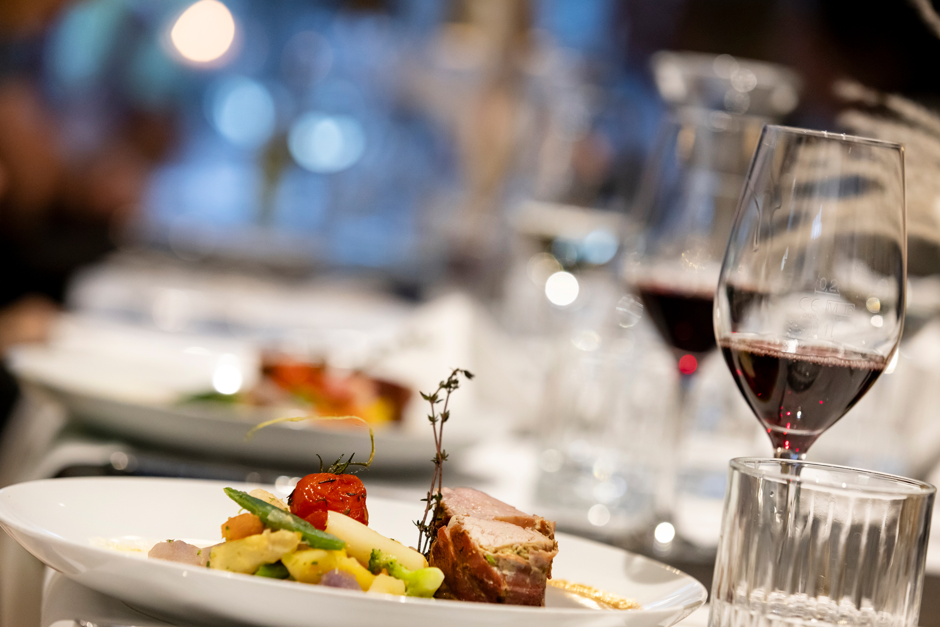 modern angerichtetes Gericht mit Fleisch und Gemüse mit einem Glas Rotwein